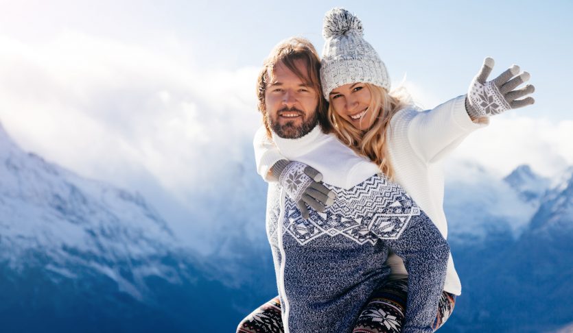一起使用在雪的爱恋的夫妇室外。在山的寒假。男人和女人穿着针织的衣物在周末获得乐趣。