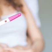 选择性聚焦幸福夫妇拥抱与怀孕测试阳性在卧室。