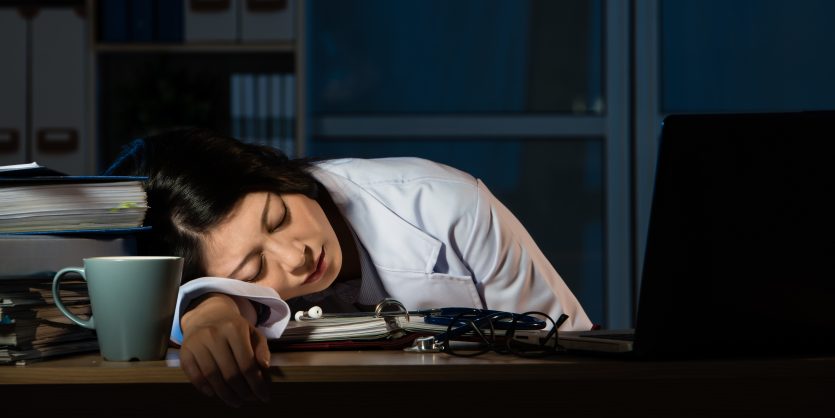 医生在诊所的桌子上睡得很累。美丽的混血亚洲华人女性模特。医疗健康理念